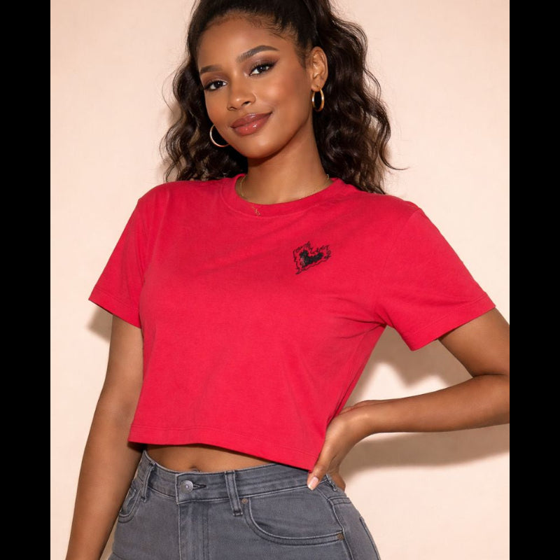 Woman wearing a red t-shirt with a small logo and gray pants against a beige background